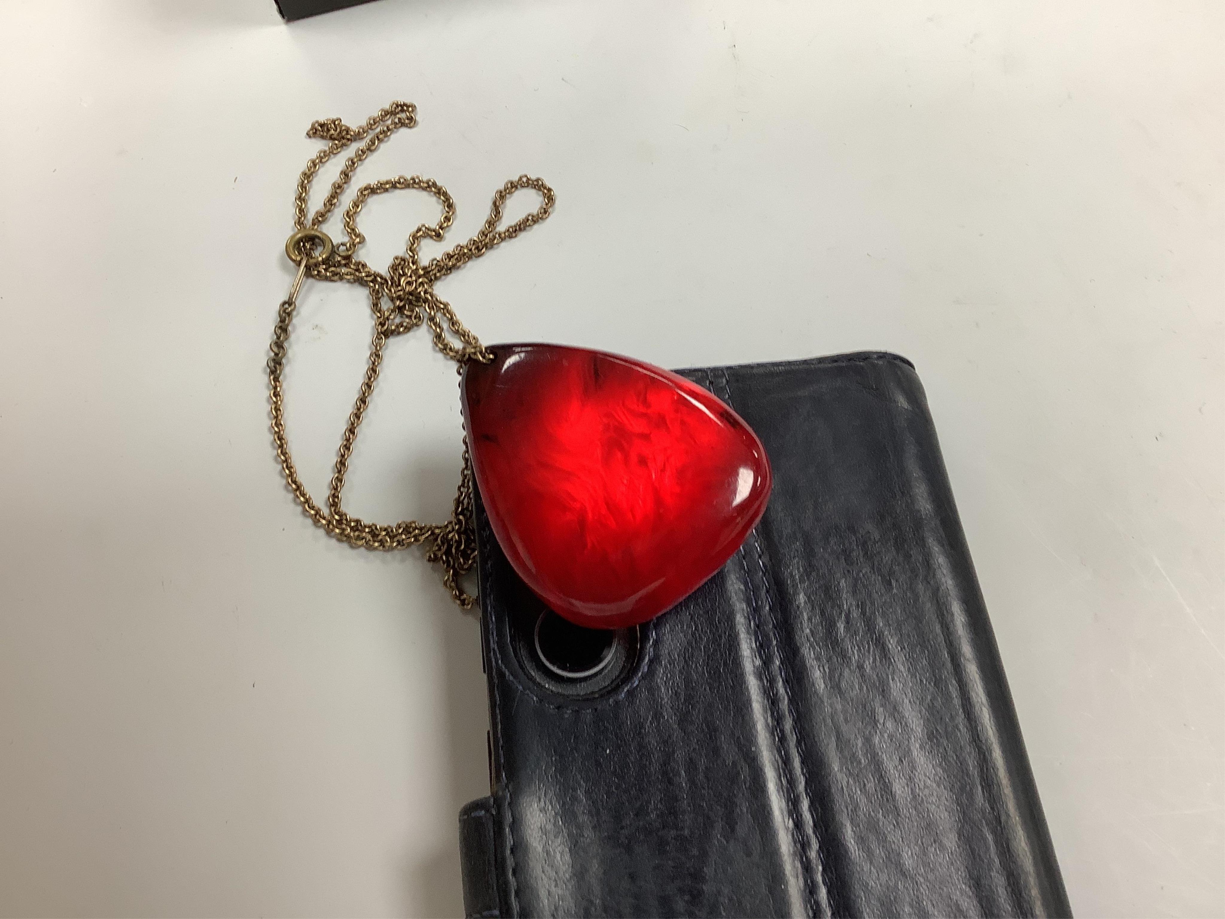 A cherry bakelite 'amber' necklace and pendant, comprising: a necklace composed of cherry-coloured bakelite beads measuring approximately 10 - 26mm, length 90cm, gross weight 72 grams; and a drop-shaped pendant, length 5